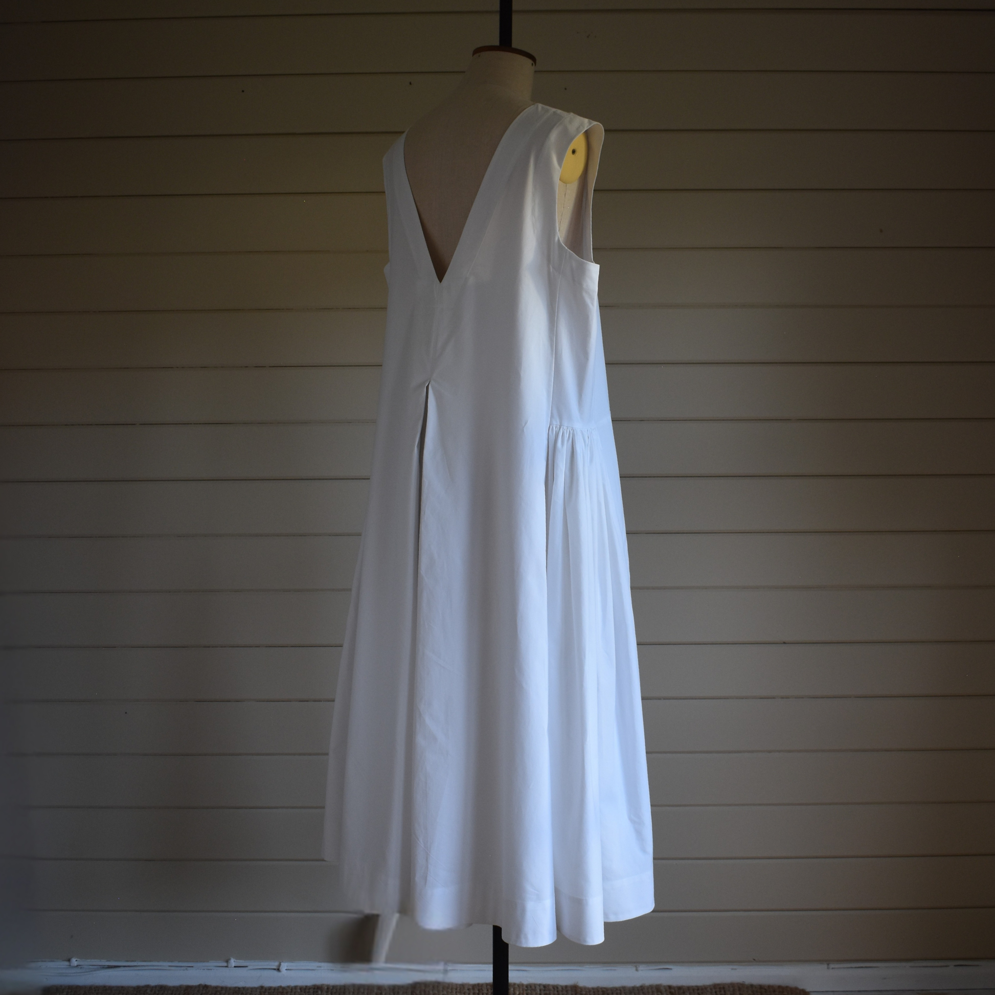 White dress on a mannequin against a wooden paneled wall